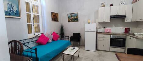 A compact living space with a bed, a small table, a kitchenette, and a dining area.