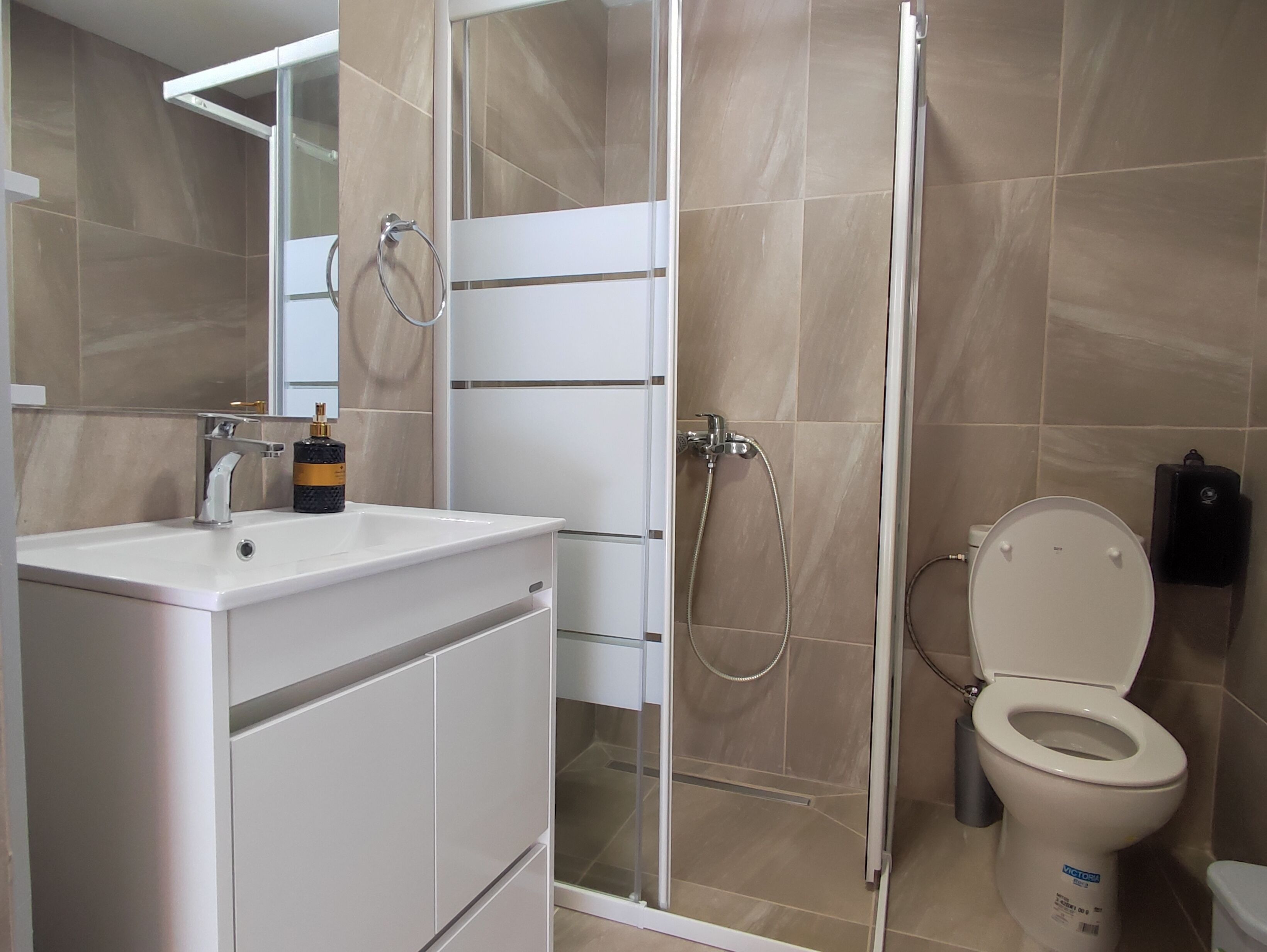 A modern bathroom with a shower, toilet, and sink.