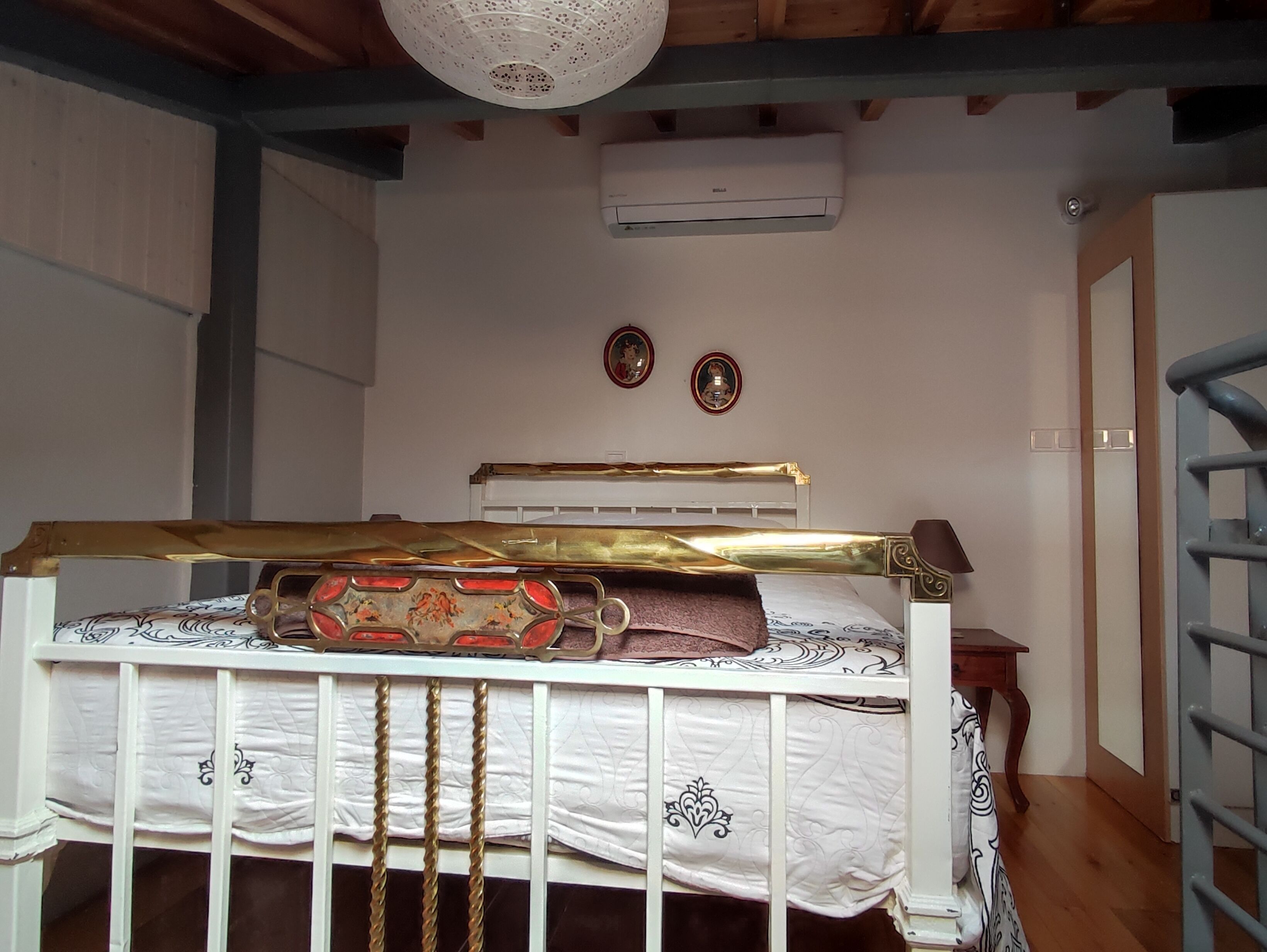 Un dormitorio con una cama blanca, cabecera de madera, ventilador de techo blanco y aire acondicionado de pared.