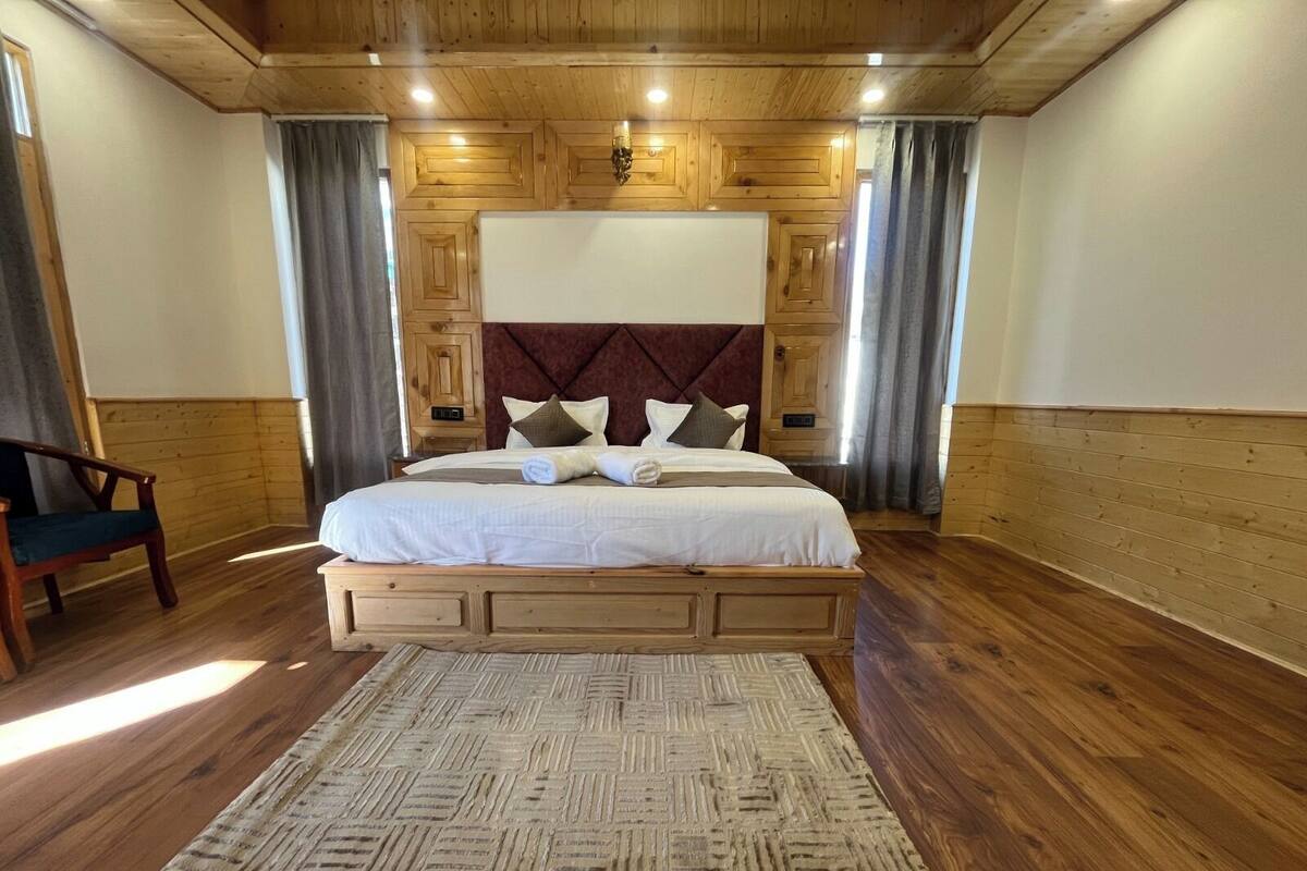 Ein Schlafzimmer mit Holzwänden, einem großen Bett, einem Nachttisch aus Holz und einem Sessel.
