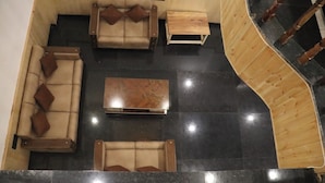 A spacious living area with a sofa set, a coffee table, and a wooden staircase. - Hotel Mountain Blue Manali (Manali)