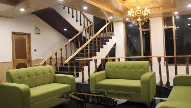 A room with a staircase, green upholstered chairs, and a chandelier. - Hotel Mountain Blue Manali (Manali)