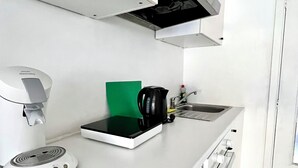 A modern kitchen with a coffee machine, a kettle, and a green cutting board on the counter. - Studio à 800 m de la Grand Place (Brussels)