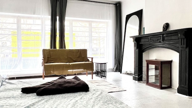 A spacious bedroom with a large bed, a sofa, a fireplace, and a view of the outside through a large window. - Studio à 800 m de la Grand Place (Brussels)