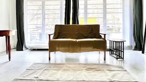 A room with a large window, a sofa, a small table, and a rug. - Studio à 800 m de la Grand Place (Brussels)