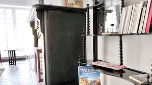 A room with a black bookshelf, a framed picture on the wall, and a window with curtains. - Studio à 800 m de la Grand Place (Brussels)