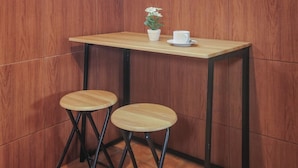 A small wooden table with a white cup and a potted plant. Two stools are placed in front of the table. - Navalia Villa Bedugul (Baturiti)