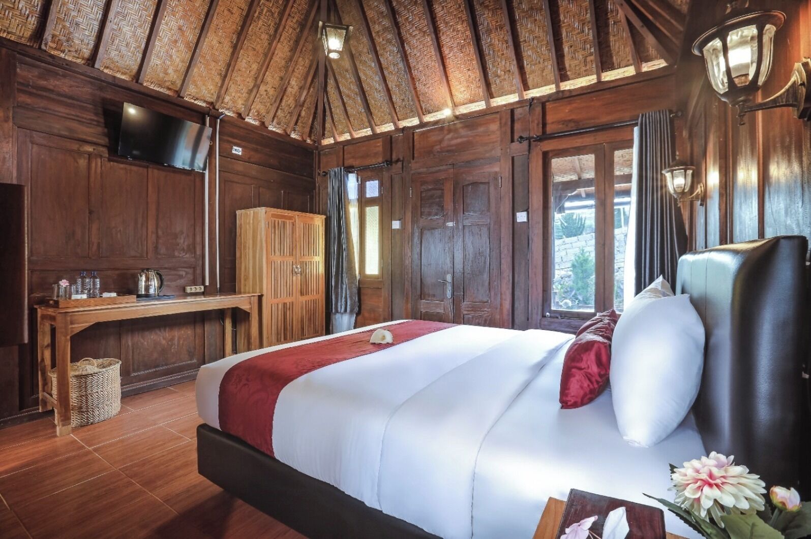 Ein Zimmer mit Holzboden, einem Bett, einem Schreibtisch und einem Fernseher.
