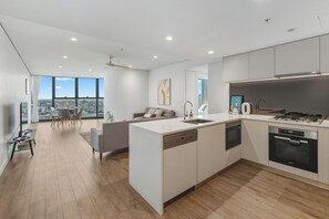 A modern kitchen with a central island, built-in appliances, and a dining area with a view.