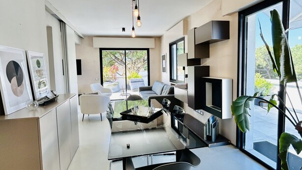 A modern living room with a sofa, coffee table, and TV. There are large windows and a plant. - The Flexrent Port - Abyssinia (Riccione)
