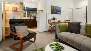 Ein modernes Wohnzimmer mit einem schwarzen Ledersessel, einem grauen Sofa und einem Essbereich mit einem Holztisch und Stühlen.