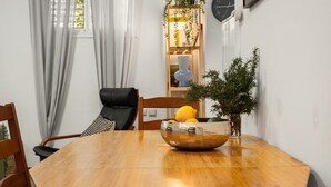 Ein Essbereich mit einem Holztisch, Stühlen, einer Obstschale und einem Blumentopf.