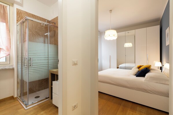 A modern bedroom with a glass shower enclosure, a bed with white bedding, and a large mirror. - notaMi - Ronchetto Lodge Navigli (Milan)