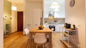 Una cocina moderna con una mesa de madera, sillas blancas y un frutero.