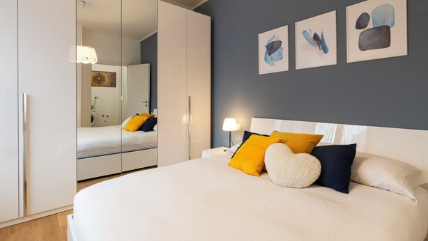 Un dormitorio moderno con una cama grande, un armario y un espejo.