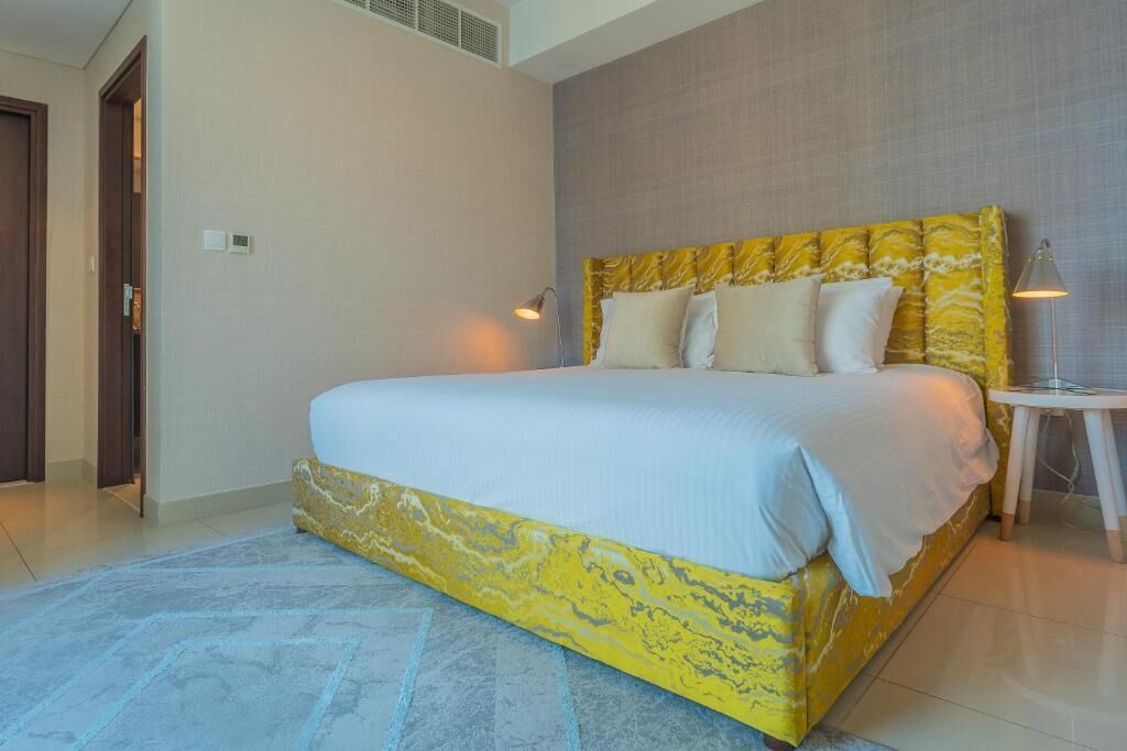 A modern hotel room with a large bed, a small side table, and a nightstand.