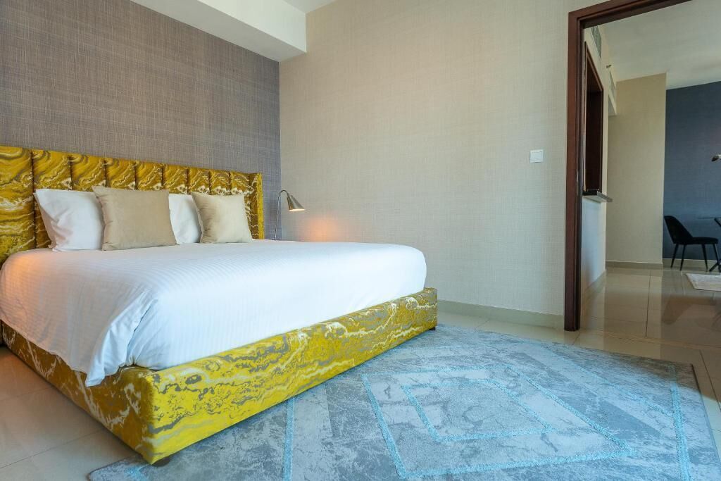 Un dormitorio con cama, mesita de noche y puerta que da a otra habitación.