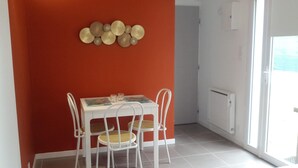 Un comedor con una mesa y sillas blancas, una pared roja y una ventana con vistas.
