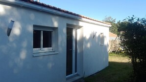Una casa de una sola planta con fachada blanca, una ventana pequeña y una puerta.