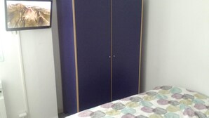 Un dormitorio con cama, armario y televisor en la pared.