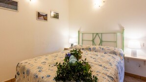 A bedroom with a bed, a bedside table with a lamp, and wall-mounted lights. - Beautiful apartment for 10 guests with WIFI, A/C, pool, patio and pets allowed (Civezza)