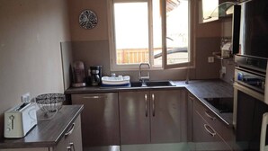 A compact kitchen with a window, a built-in oven, and a microwave. - Chez Malya, quiet house near the lake (Charavines)