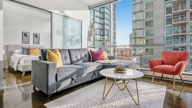 A modern living room with a grey sofa, red chair, and a round coffee table.