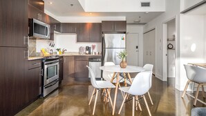 A modern kitchen with dark wood cabinets, stainless steel appliances, and a white dining area with a round table and chairs.