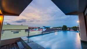 Una piscina al terrat amb vistes a edificis i un cel al capvespre.