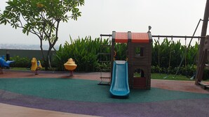 A playground with a slide, swings, and climbing structures. - Cosmy Benson 38 Apartment (Surabaya)