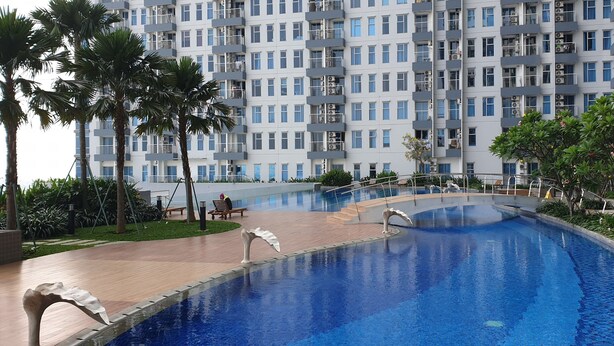 A modern hotel with a swimming pool, palm trees, and a well-maintained garden. - Cosmy Benson 38 Apartment (Surabaya)