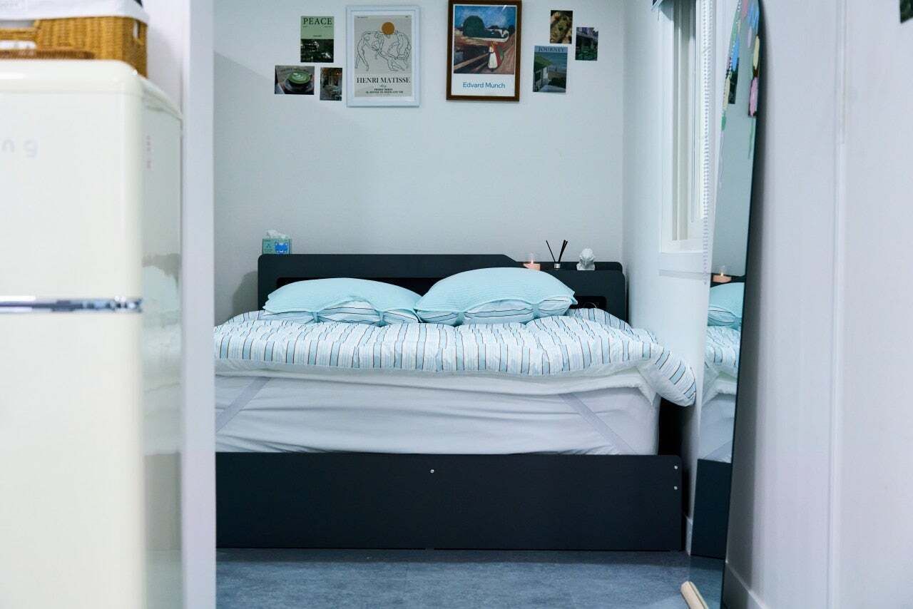 A bedroom with a bed, a dresser, and a wall with framed pictures.