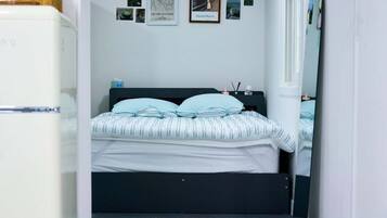 A bedroom with a bed, a dresser, and a wall with framed pictures.