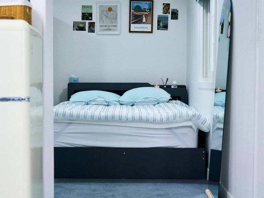A bedroom with a bed, a dresser, and a wall with framed pictures.