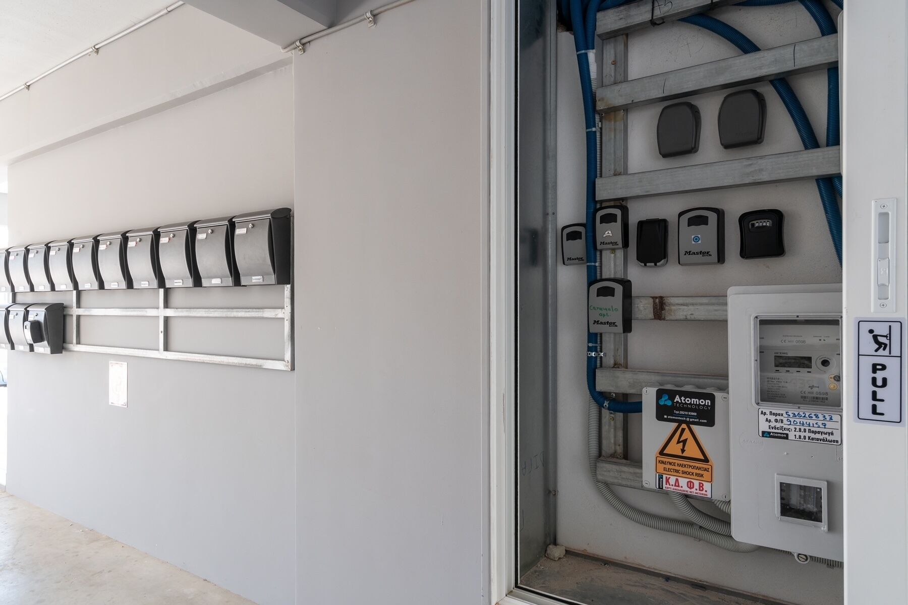 A utility room with electrical panels, a fire alarm, and a control panel with a warning sign.