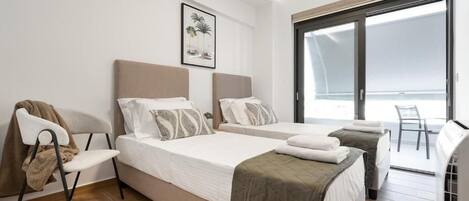 A hotel room with two beds, a chair, a large window, and a door leading to a balcony.