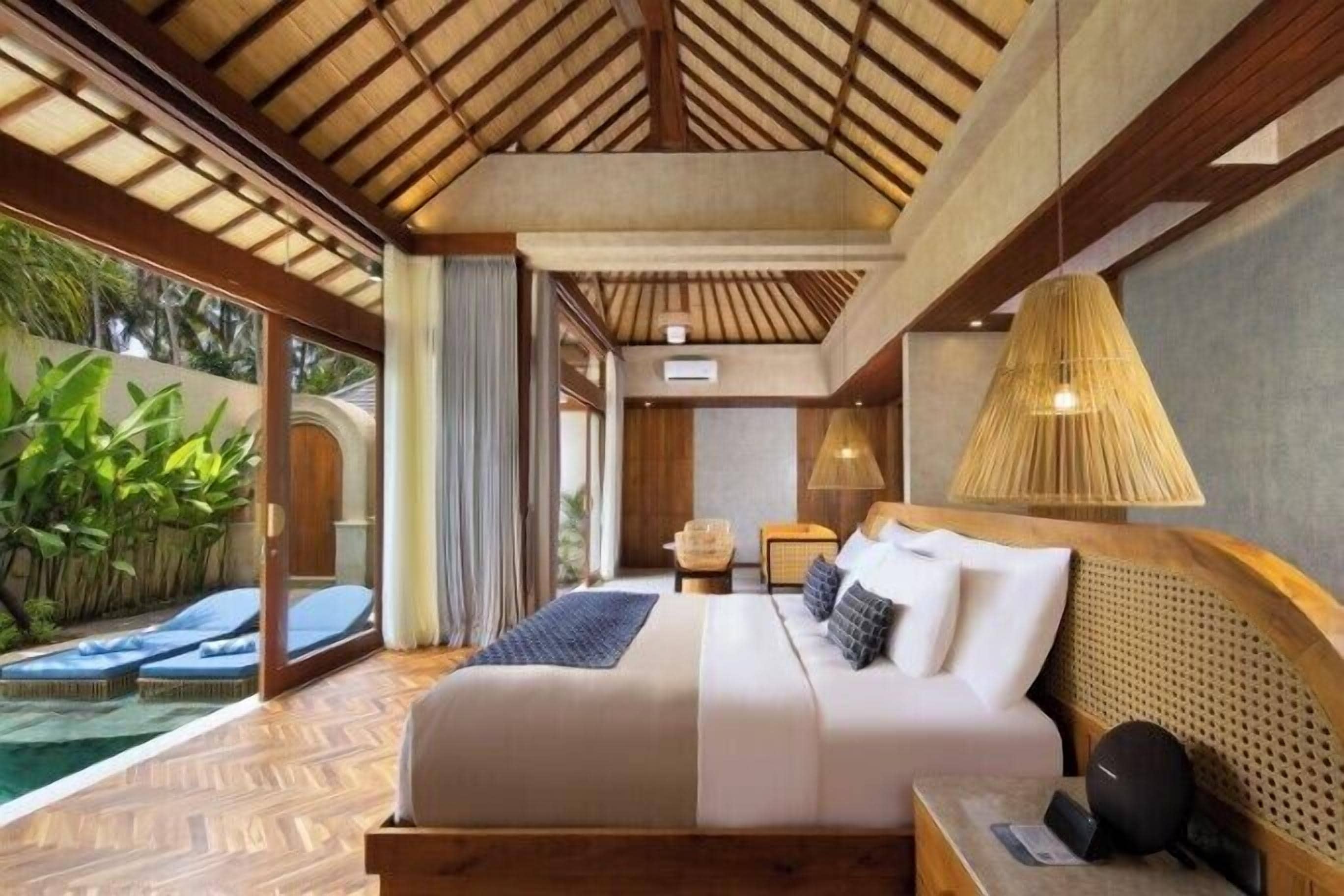 Un dormitorio con cama, mesita de noche, lámpara y vista a una piscina.