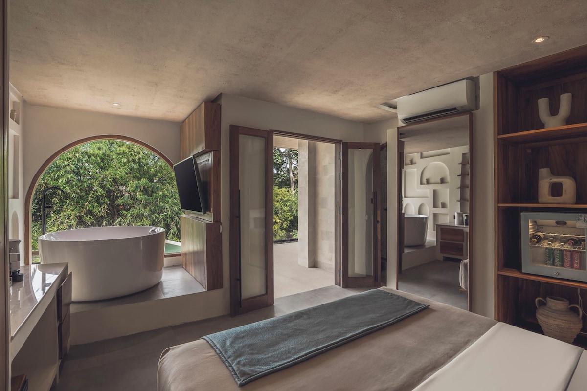 A modern bathroom with a large bathtub, a mirror, and a shower area.