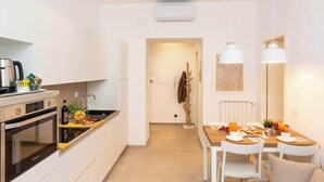 A modern kitchen with a built-in oven, a coffee machine, and a dining area with a table set for breakfast.
