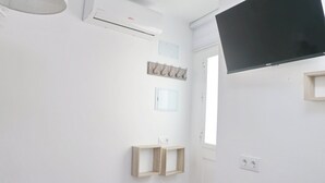 Un baño moderno con aire acondicionado de pared, un televisor de pantalla plana y un ventanal que proporciona luz natural.
