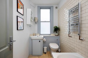 Une petite salle de bain comprenant un lavabo, des toilettes et une baignoire.