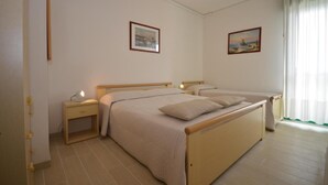 A bedroom with a double bed, two bedside tables, and two framed pictures on the wall.
