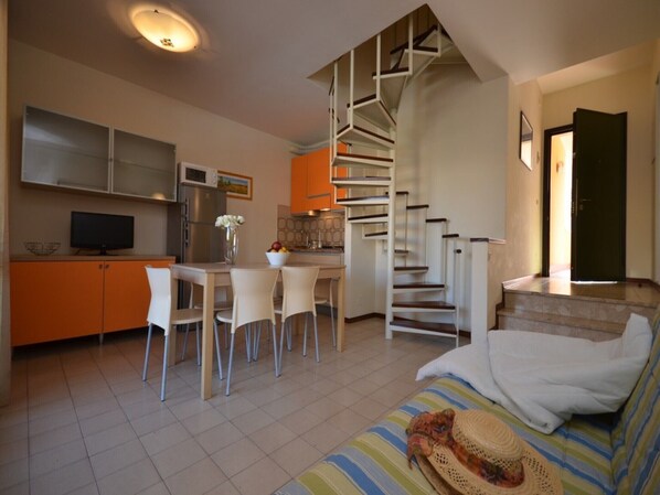A compact living space with a kitchen, dining area, and a staircase leading to an upper level.