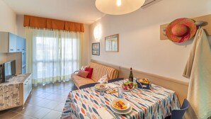 Una sala de estar acogedora con un sofá, una mesa de comedor y un televisor.