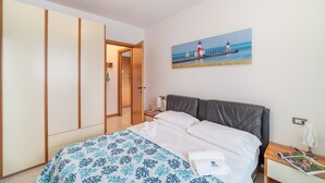 Ein Schlafzimmer mit einem Bett, einem Nachttisch, einem Bild eines Piers und einem Kleiderschrank.