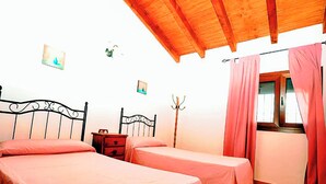 Quarto com duas camas de solteiro, teto de madeira, mesa de cabeceira, porta-casacos e janela com cortinas.