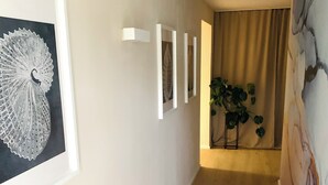 A hallway with framed artwork, a plant, and a marble wall.