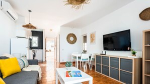 A modern living room with a sofa, coffee table, TV, and kitchen in the background. - CASTELLSOL 201 (Arenal d´en Castell)