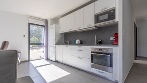A modern kitchen with white cabinets, a built-in oven, and a microwave.