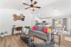 A modern living room with a grey sofa, a coffee table, and a ceiling fan.
